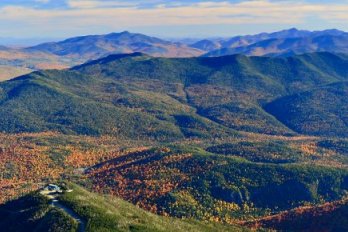 Fall scene of forest-clad Adirondack mountains upon mountains fading into distance.
