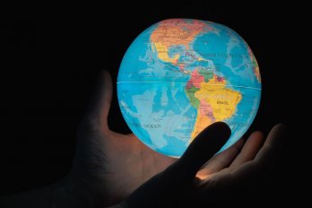 A hand holding a glowing inflatable globe with North America shown at center