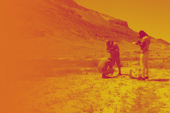 Yellow-Orange tone black and white photo of students conducting fieldwork in desert