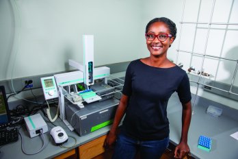 PhD student Marsha allen smiling at camera, standing in front of analytical equipment