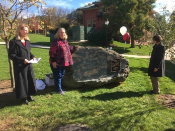 Dr. Julie Brigham-Grette, Johanna Andersen-Pratt, and Dean Serio stand in front of a boulder of pillow basalt from the Ordovician Hawley Formation in the Morrill courtyard