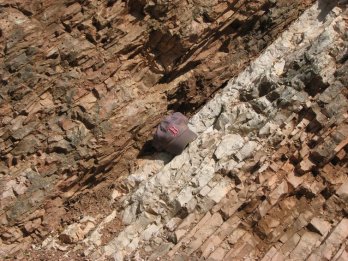  Rocks near Gubbio, Italy, change in color and texture at the line indicating the Cretaceous-Paleogene extinction event that wiped out the dinosaurs 66 million years ago. A baseball hat shows scale. Photo by Dr.'s Robert DeConto and Mark Leckie, UMass Geosciences, CC BY-ND 