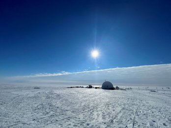 A quonset hut on a flat, featureless field of snow and ice in Anarctica