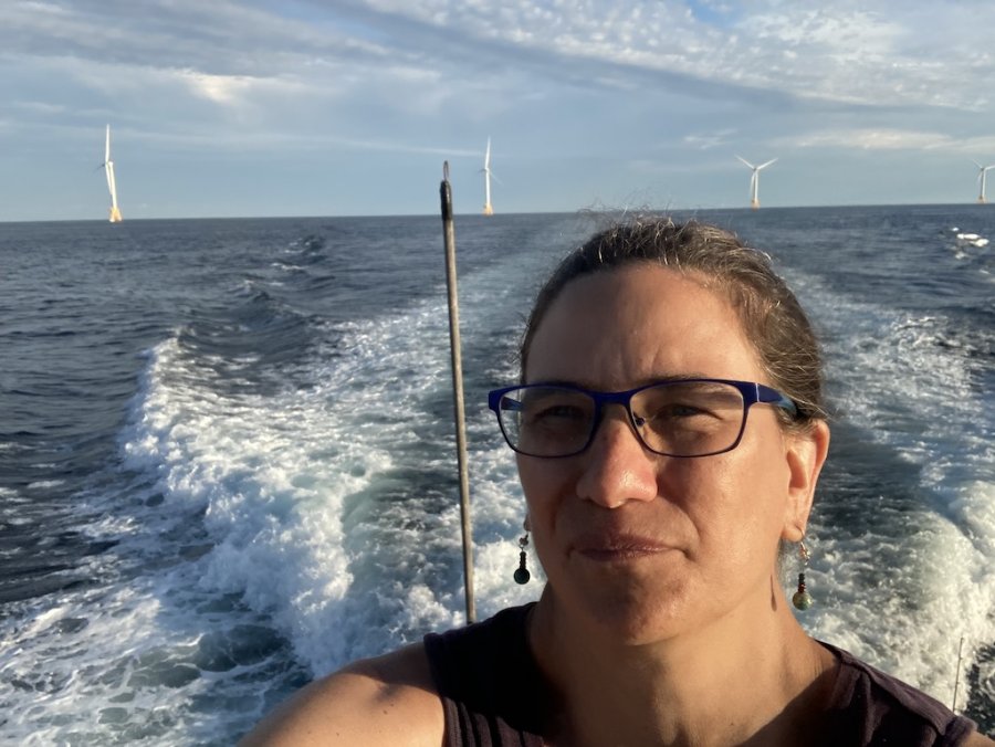 Picture of Dr. Vogel on a boat in front of ocean-mounted wind turbines
