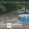 A screenshot of a CBS Boston video showing a backyard with an above ground pool being inundated with floodwater