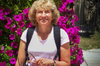 Dr. Sheila Seaman in front of purple bougnavilla bush, smiling at camera.