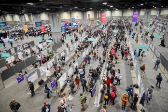 Photograph looking down on the poster hall of the 2018 AGU fall meeting, with several hundred people congregated in multiple rows of poster-stands, looking at what is hung on them.