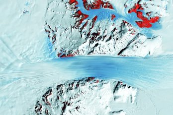  A satellite image shows the long flow lines as a glacier moves ice into Antarctica’s Ross Ice Shelf, on the right. The red patches mark bedrock. USGS 