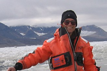 Dr. Julie Brigham-Grette smiling in front of Arctic Lake