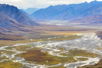 Photo of high artic mountain valley, with braided river winding its way though wide floodplain