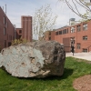 Car-sized boulder of pillow lava sitting on lawn between two brick buildings built as fallout shelters in the 1950s.