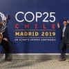 Dr. Benjamin Keisling, Dr. Julian Reyes, and Hannah Baranes, all in formal attire, striking poses in front of wall with dark blue COP25 logo.