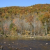 Autumn scene of wooded hills just past peak color, with tannin-colored Deerfield River in foreground.