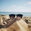 A pair of sunglasses resting on the beach.  Photo by Ethan Robertson via Unsplash
